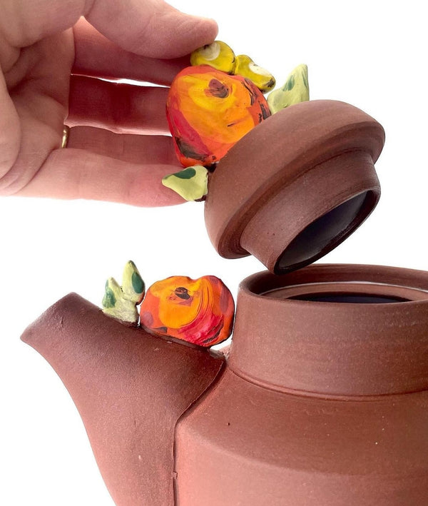Cheerful red clay ceramic teapot with floral details.