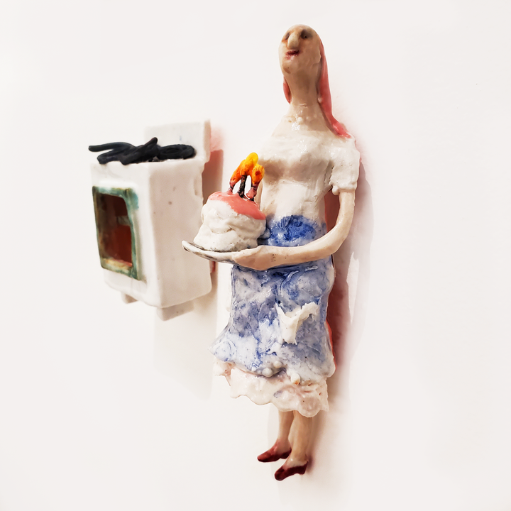 Cake Wife: Two-part ceramic sculpture of a woman holding a cake, and an oven. Designed to hang on the wall, each hangs separately from a metal loop.