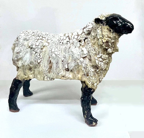 A ceramic sculpture of a Suffolk sheep with a distinctive crackled glaze, predominantly in shades of white and black.