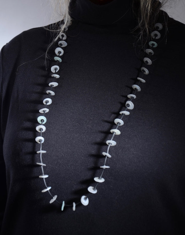 Necklace of stacked flat glass beads in soft grey with black rubber cord, 40". The 40 beads are around 1.5cm in diameter.