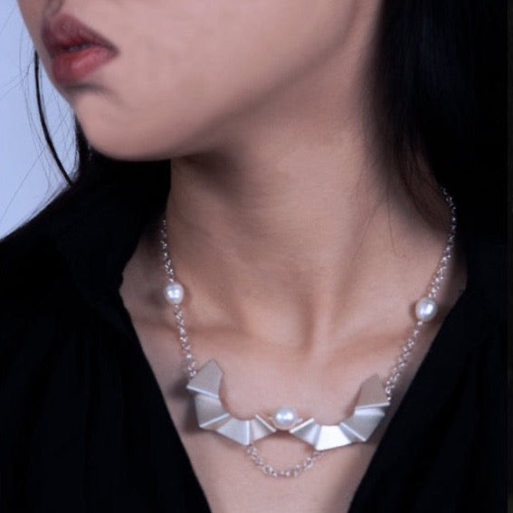 Ladder of human progress necklace, 2022.  Sterling silver necklace with a 12mm and 10mm white pearls. The silver elements were created utilizing 3D printing technology.  7.5 × 4.5 × 1.5 cm