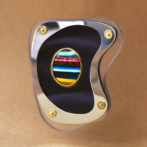 Decorative brooch with a colorful striped center and metallic frame 