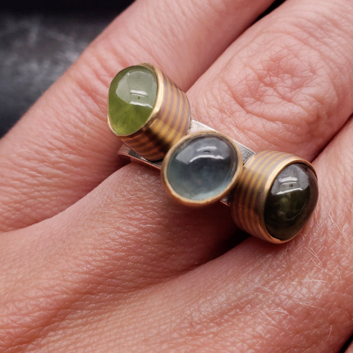 Trilogy rings, made from sterling silver, 18K grey and yellow gold with green and blue cab sapphires 