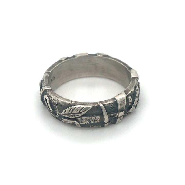 "Forest floor" ring of sterling silver, with oxidization. The shapes of branches, leaves and stones fully surround the 7mm band.