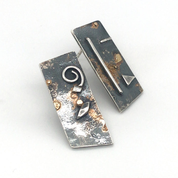 Asymmetrical oxidized sterling silver stud earrings with gold details. Each 2.5 x 1 cm.