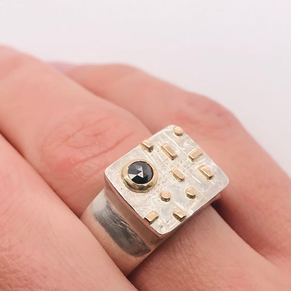 Sterling silver signet ring with a black diamond and 14k yellow gold details. 2.3 x 2.6 x 1.3 cm.