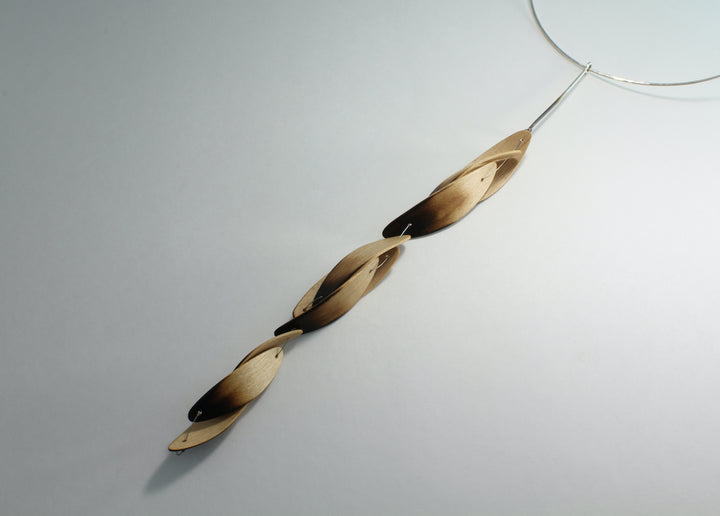 Burnt Pod neckpiece, 2018. Laminated bent and scorched maple wood, hand-formed, forged, and  patinated sterling silver wire, and stainless steel cable.