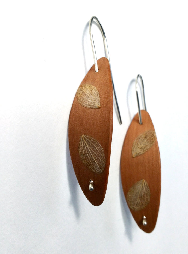 Cherry Foraged Pod earrings, 2023. Hand laminated and bent cherry wood earrings, with sterling silver and foraged plant material.