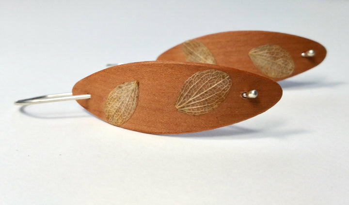 Cherry Foraged Pod earrings, 2023. Hand laminated and bent cherry wood earrings, with sterling silver and foraged plant material.