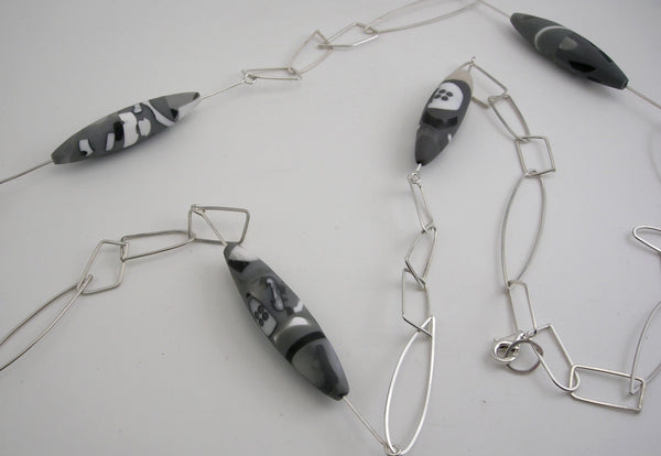 Sterling silver long mixed geometric link necklace with buttons floating within resin elements. 104 cm in length.  