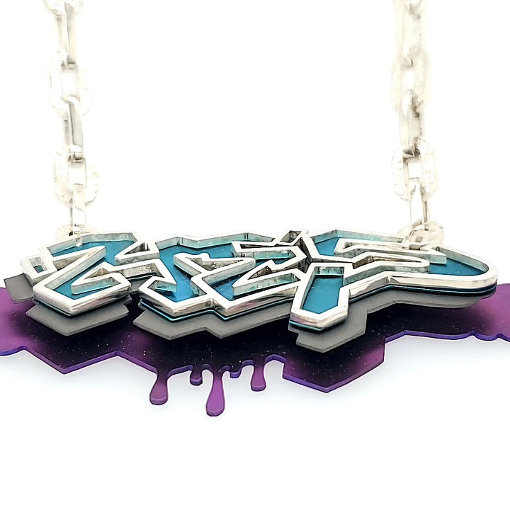Purple Nights, 2022 - A Hand cut and riveted graffiti-style pendant with Tsavorite garnets is suspended on a cast sterling silver link chain.