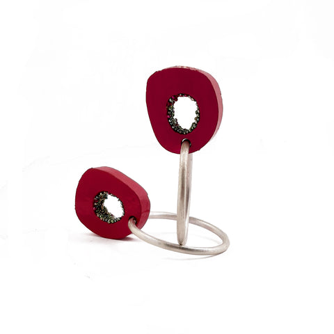Hoop earrings of pink lacquered bovine bone with sterling silver hoops. These are stud earrings; the hoops hang suspended beneath the earlobe.