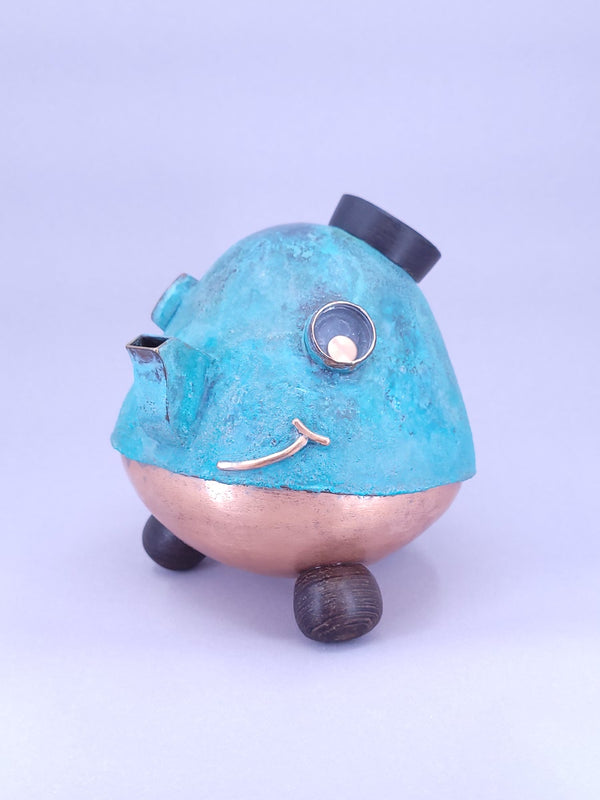 Happy Teapot Piggy Bank - A smiling teapot-shaped piggy bank of cheerful blue patinated copper, with copper and glass googly eyes. 