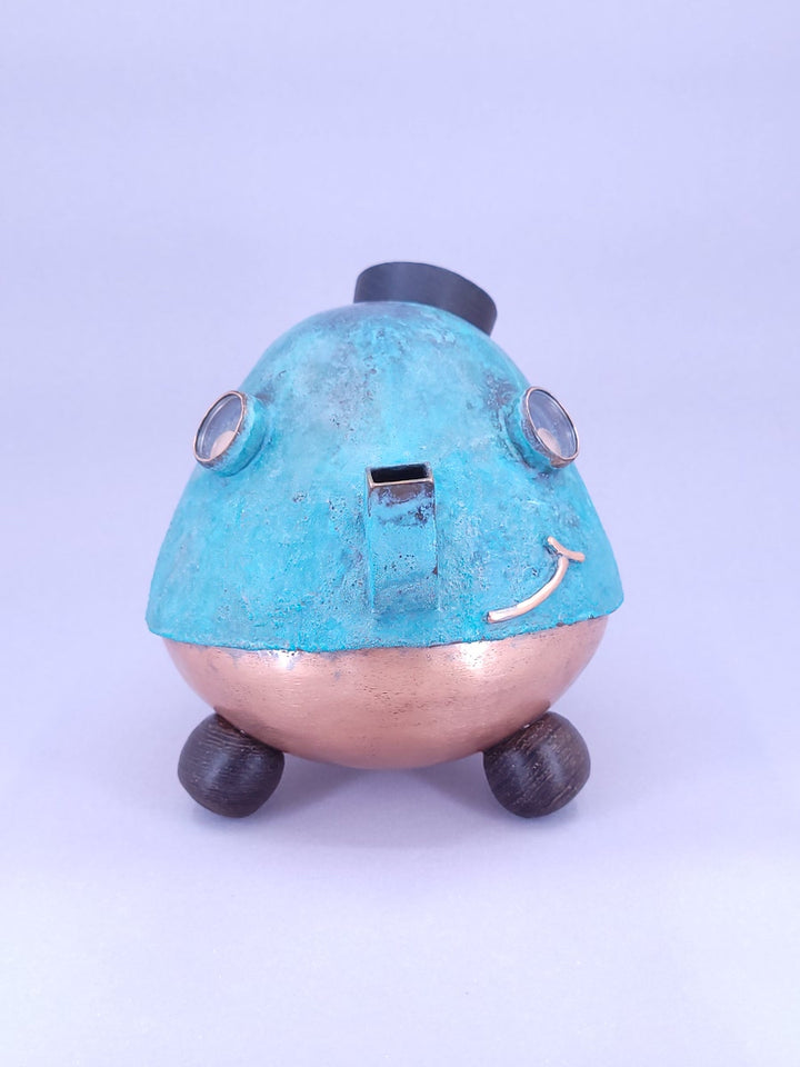 Happy Teapot Piggy Bank - A smiling teapot-shaped piggy bank of cheerful blue patinated copper, with copper and glass googly eyes. 