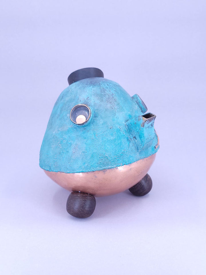 Happy Teapot Piggy Bank - A smiling teapot-shaped piggy bank of cheerful blue patinated copper, with copper and glass googly eyes. 