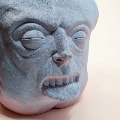 Holding Back I - large ceramic two-sided sculpture of a figure biting their tongue, with blue and pink gouache paint.
