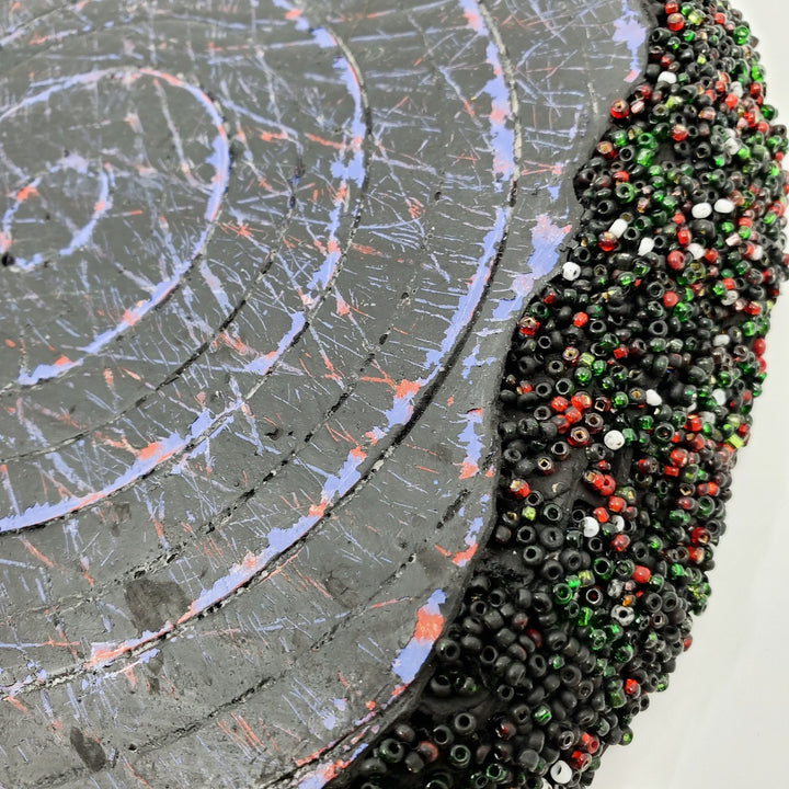 Blue & Black: Mixed media wall sculpture constructed with a corrugated cardboard base. It is painted with acrylics, and adorned with green and red glass beads.