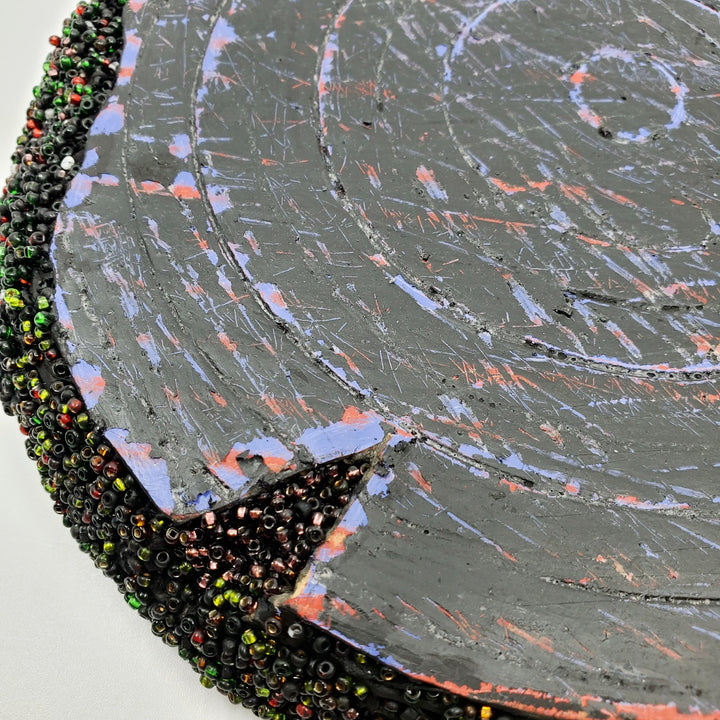 Blue & Black: Mixed media wall sculpture constructed with a corrugated cardboard base. It is painted with acrylics, and adorned with green and red glass beads.