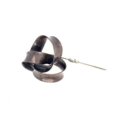 Lapel pin. Nickel knot-shaped design with sterling silver pin.
