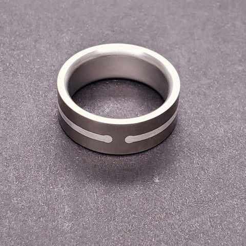 A subtle but strong inlaid line of fine silver circles this 8 mm titanium band, interrupted on either side by two dots. Size 9 1/4.