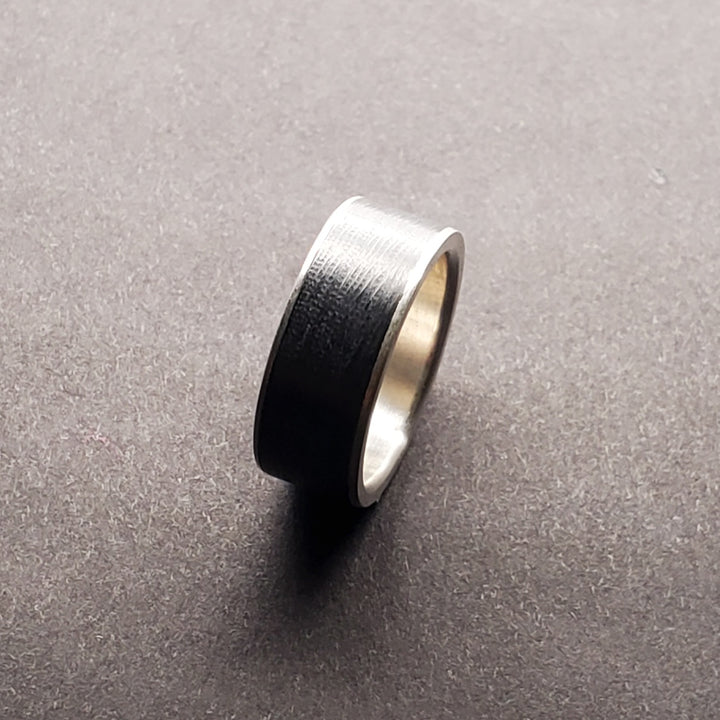 Striking black niobium ring with a fine silver sleeve. The niobium has a subtle, rippled texture. This ring is size 5 3/4 with an 8mm band.