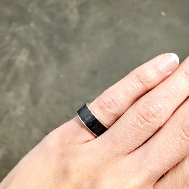 Striking black niobium ring with a fine silver sleeve. The niobium has a subtle, rippled texture. This ring is size 5 3/4 with an 8mm band.