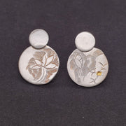 Hand-tooled sterling silver stud earrings. Keum-boo gold is worked into the surface of the flower-patterned silver disks.