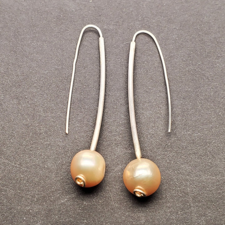 Freshwater pearl dangle earrings with hand formed sterling silver. The 10mm peachy-pink pearls hang gently from long hooks.