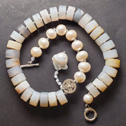 Necklace of agate, fine silver, and freshwater pearls, hand-knotted between each bead. A large baroque pearl dangles from from one side.