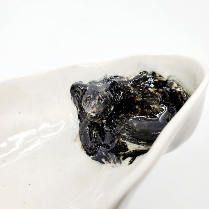 Multi-fired porcelain dish depicting a resting black bear. 