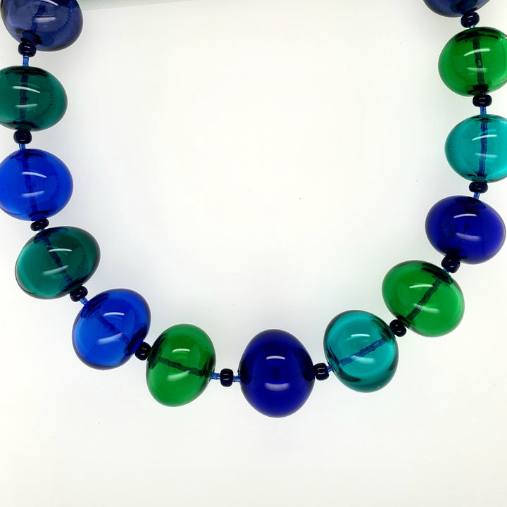 Hollow beaded necklace with sead beeds in various shades of blue made from flameworked glass on a 20" chain with sterling silver clasp.