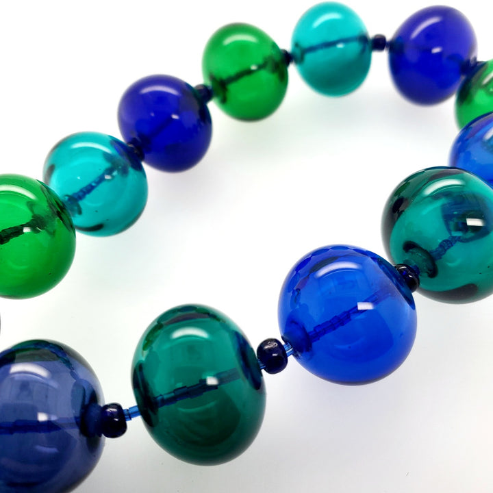 Hollow beaded necklace with sead beeds in various shades of blue made from flameworked glass on a 20" chain with sterling silver clasp.