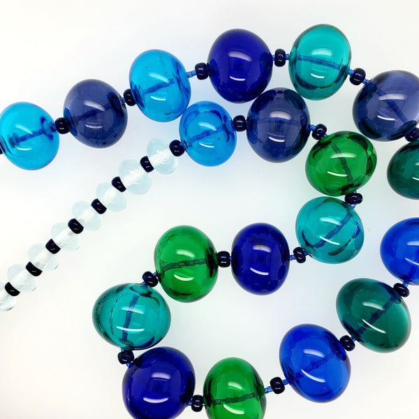 Hollow beaded necklace with sead beeds in various shades of blue made from flameworked glass on a 20" chain with sterling silver clasp.