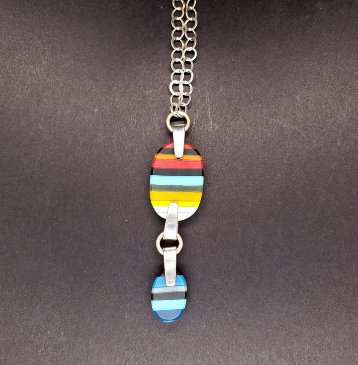 Multicoloured striped carved double-pendant made from kilnformed glass on a 26" sterling silver chain.