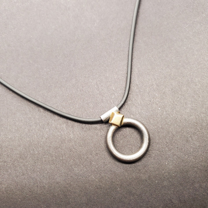 Oxidized matte sterling silver circle measuring 2 x 1.5 cm on a 48 cm fine rubber neck ring.