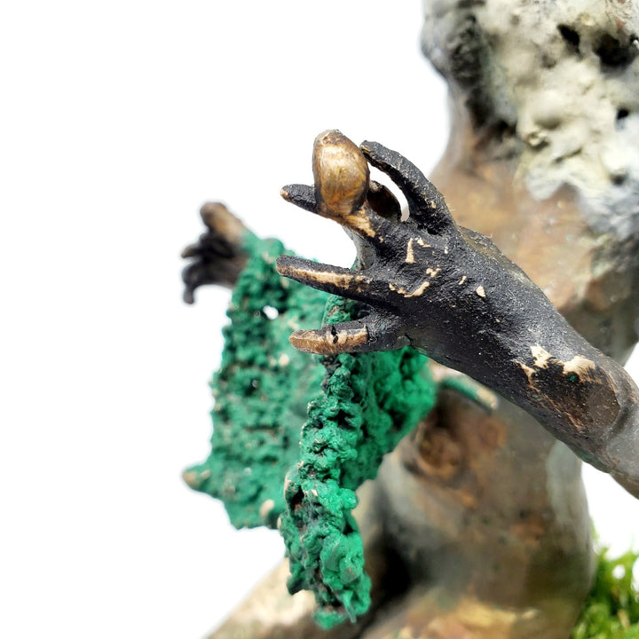 Domestic Sheep: Elsie Mae.  A bronze figure with a sheep's head and a woman's body sits on a turf-covered bench, peacefully knitting. 1 of 1.