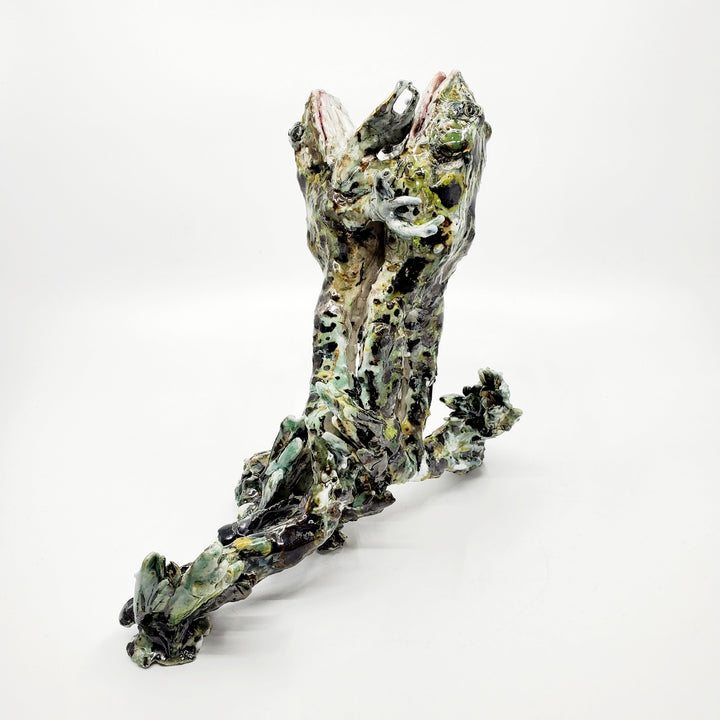 Porcelain sculpture of two frogs in an embrace, leaping together from the water. Pond growth reaches up around their feet. Richly textured with both colour and line, these spotted green frogs are streaked with gold lustre. 