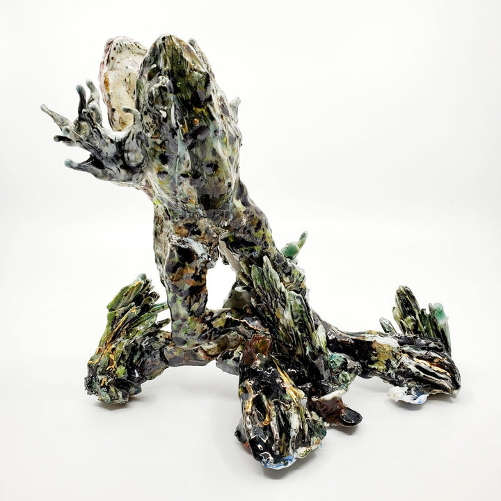 Porcelain sculpture of two frogs in an embrace, leaping together from the water. Pond growth reaches up around their feet. Richly textured with both colour and line, these spotted green frogs are streaked with gold lustre. 