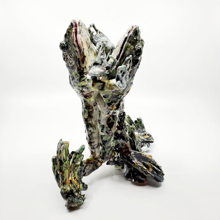 Porcelain sculpture of two frogs in an embrace, leaping together from the water. Pond growth reaches up around their feet. Richly textured with both colour and line, these spotted green frogs are streaked with gold lustre. 