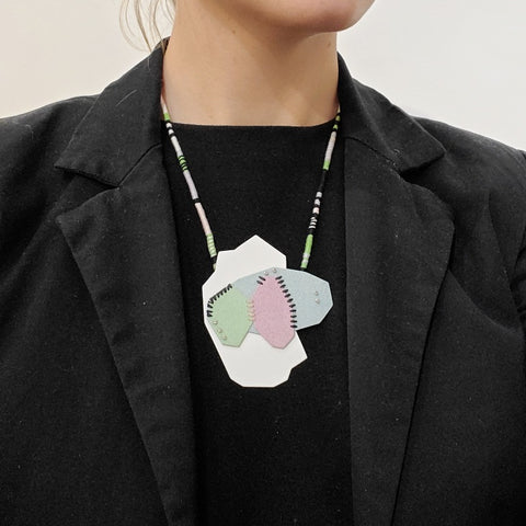 Pastel Geo Sewn Necklaces combine repurposed powder-coated copper and fibre art. The metal segments are stitched together with embroidery thread, which also winds around the cotton cord.