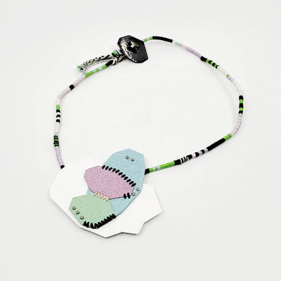 Pastel Geo Sewn Necklaces combine repurposed powder-coated copper and fibre art. The metal segments are stitched together with embroidery thread, which also winds around the cotton cord.