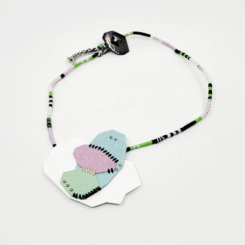 Pastel Geo Sewn Necklaces combine repurposed powder-coated copper and fibre art. The metal segments are stitched together with embroidery thread, which also winds around the cotton cord.