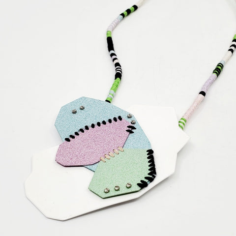 Pastel Geo Sewn Necklaces combine repurposed powder-coated copper and fibre art. The metal segments are stitched together with embroidery thread, which also winds around the cotton cord.