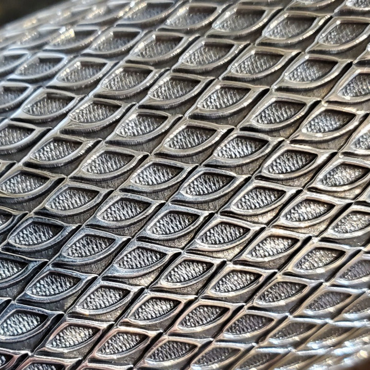 Sterling silver cuff, stamped with a geometric pattern. Within the pattern, there is a subtle texture in the oxidized spaces between the bright silver lines.