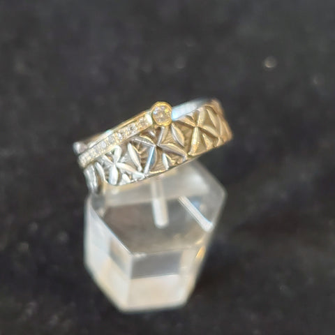 Stamped sterling silver ring. A diagonal band of diamond and 18kt yellow gold joins two rounded ends. The line is capped by a single larger diamond.