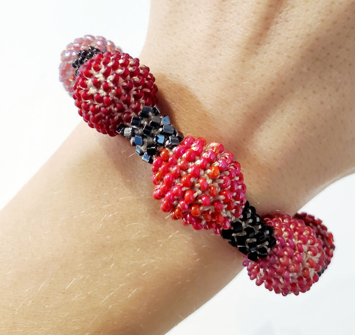 Small Purple Ball Bracelet. Purple and red glass beads are woven together with white thread. 