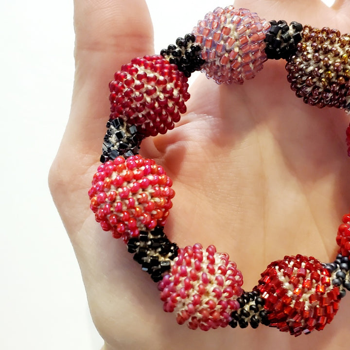 Small Purple Ball Bracelet. Purple and red glass beads are woven together with white thread. 