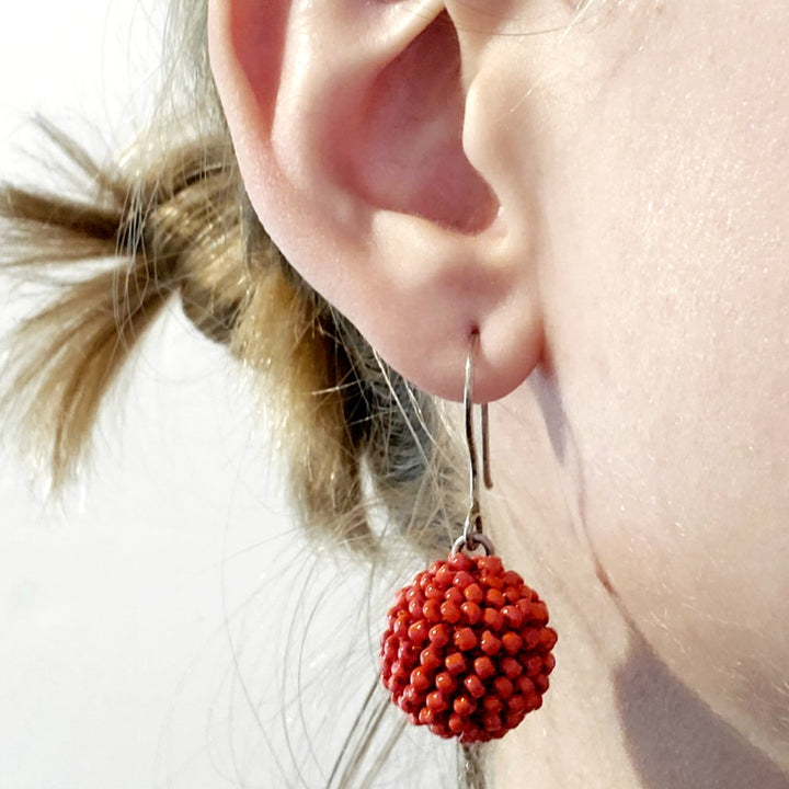 Short Orange Earrings. Red-orange glass beads are sewn in with red thread. These earrings hang 4cm long, and are on sterling silver hooks.