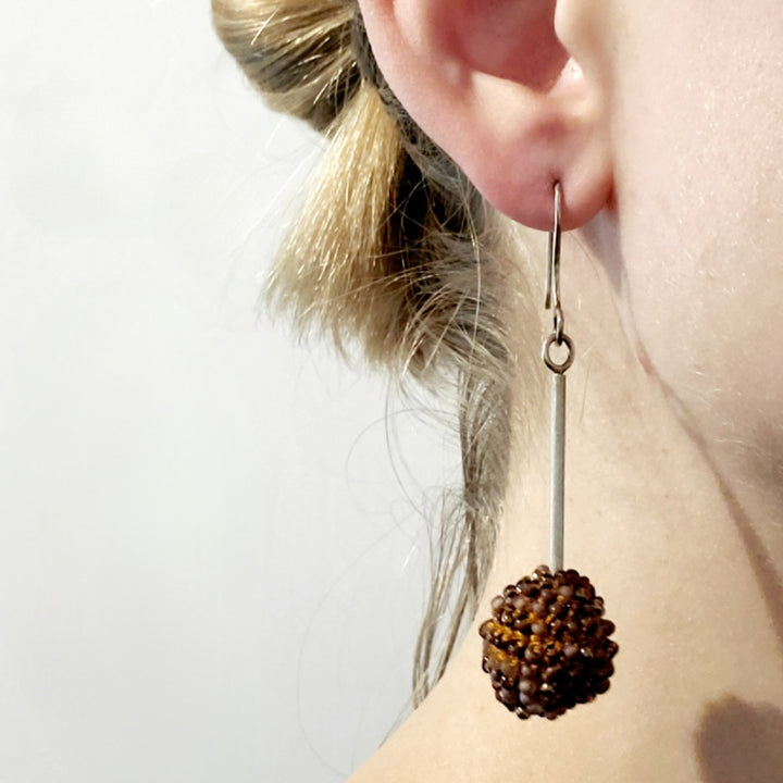 Long Purple Earrings. Purple glass beads are sewn in with golden yellow thread. These earrings hang 7cm long, and are on sterling silver hooks.