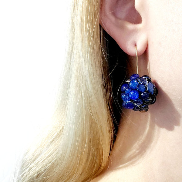 Round Blue Resin Earrings. Droplets of blue resin and sterling silver are sewn in with golden yellow thread. These earrings measure 2.2cm in diameter, and hang from sterling silver hooks.